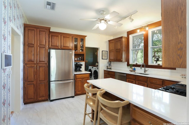 6160 Fm 2538, Marion, TX 78124 - kitchen featuring appliances with stainless steel finishes, washer and clothes dryer, a sink, brown cabinetry, and light countertops