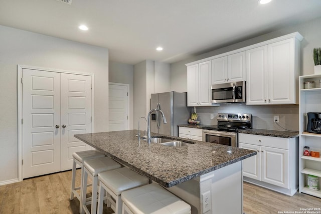 6039 Olson Blfs, San Antonio, TX 78252 - kitchen featuring appliances with stainless steel finishes, a sink, light wood-style floors, open shelves, and a center island with sink
