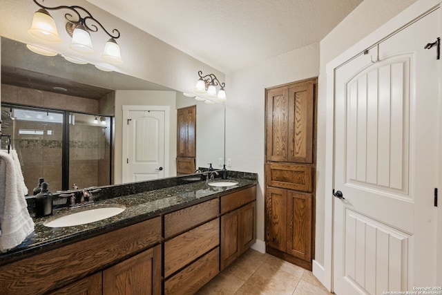 bathroom with a stall shower, tile patterned floors, double vanity, and baseboards
