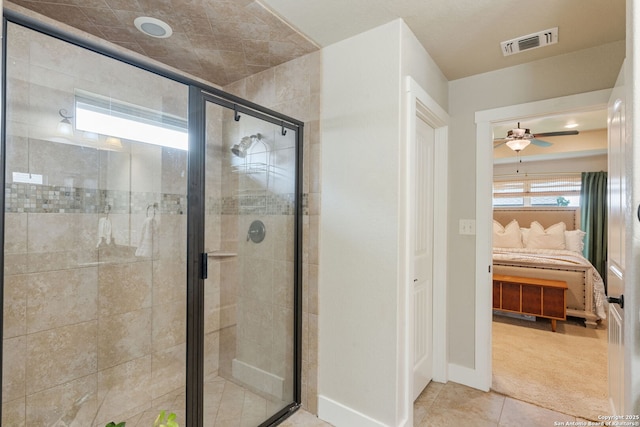 ensuite bathroom featuring a stall shower, ceiling fan, tile patterned floors, and baseboards