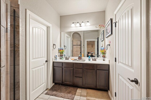 8707 Kallison Arbor, San Antonio, TX 78254 - bathroom with double vanity, a tile shower, tile patterned flooring, and a textured wall