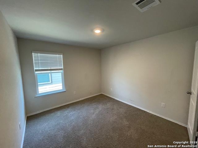 unfurnished room with dark colored carpet and baseboards