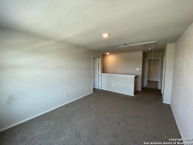 spare room with attic access and dark carpet