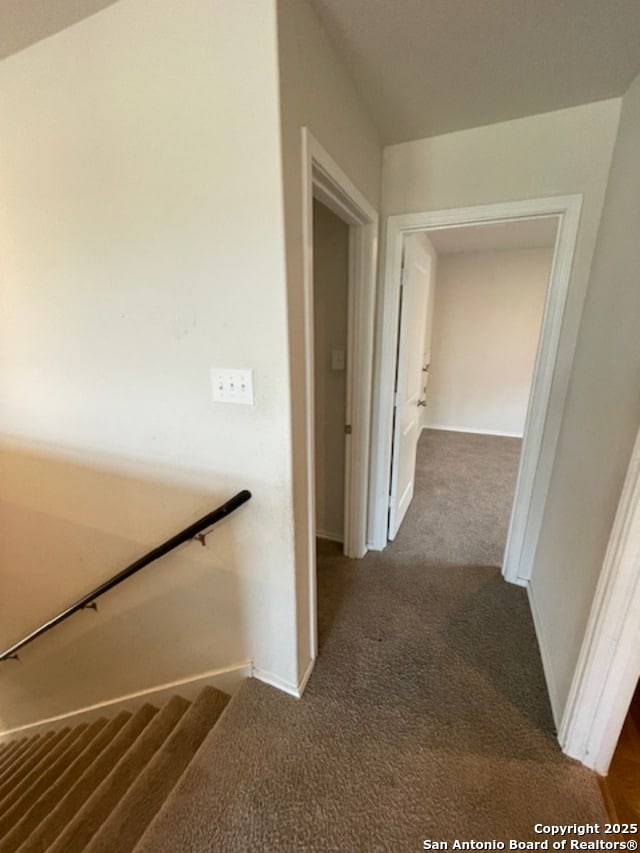 hall with carpet floors, baseboards, and an upstairs landing