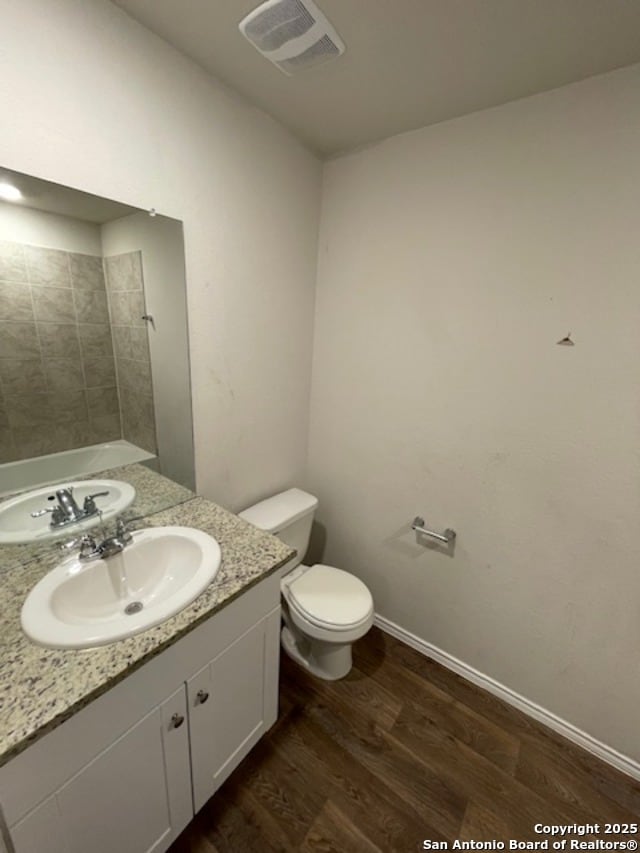full bathroom featuring wood finished floors, toilet, vanity, baseboards, and a shower