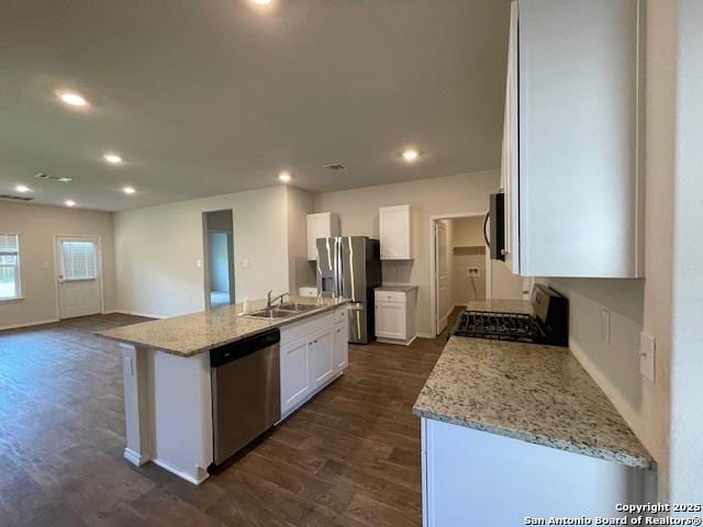 kitchen featuring stainless steel appliances, a sink, dark wood-style flooring, white cabinets, and an island with sink