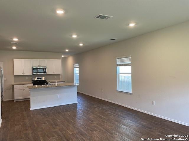 kitchen featuring stainless steel microwave, range, healthy amount of natural light, recessed lighting, and dark wood-style flooring