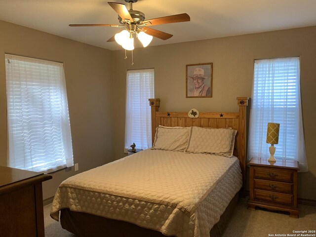 bedroom with light colored carpet and a ceiling fan