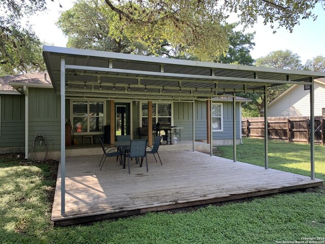back of house with board and batten siding, a wooden deck, and outdoor dining space
