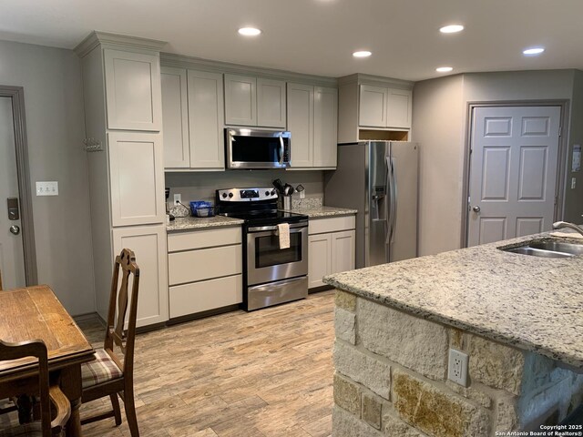 kitchen with appliances with stainless steel finishes, a sink, light wood-style floors, recessed lighting, and gray cabinets