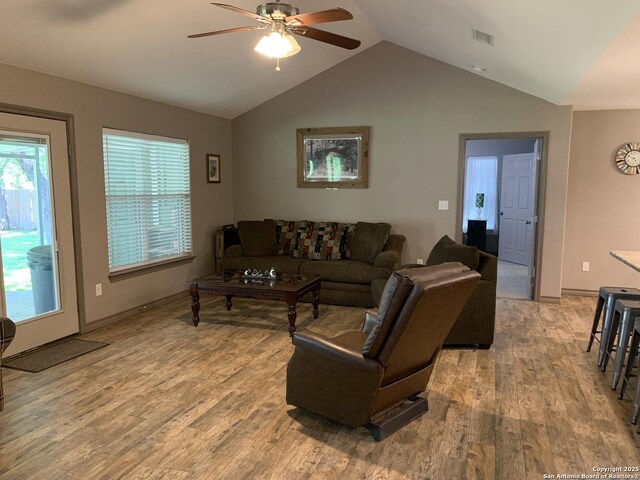 living area featuring light wood-type flooring, vaulted ceiling, ceiling fan, and baseboards