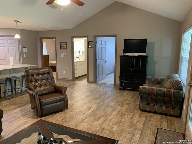 living area with light wood-type flooring, lofted ceiling, and a ceiling fan