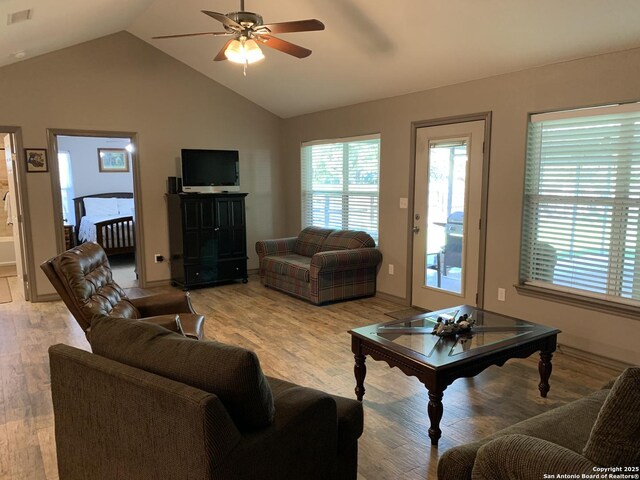 living room featuring a ceiling fan, light wood finished floors, and lofted ceiling