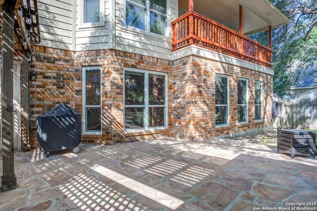 view of patio / terrace with a balcony, grilling area, and fence