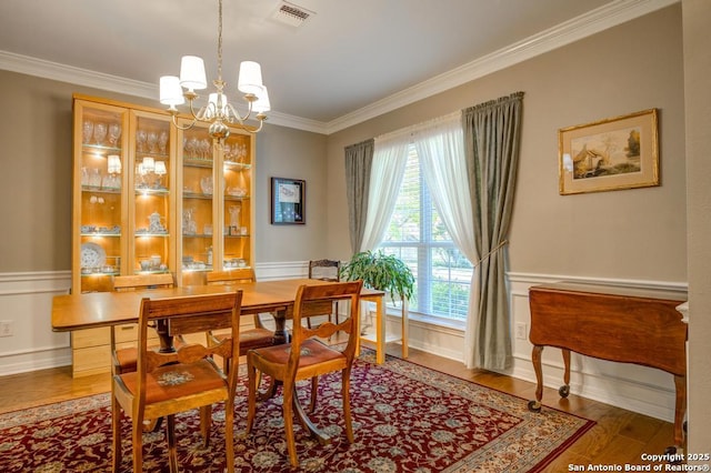dining room with crown molding, a chandelier, and wood finished floors