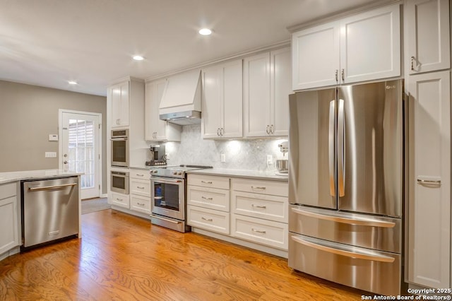 kitchen featuring stainless steel appliances, custom range hood, light countertops, tasteful backsplash, and recessed lighting