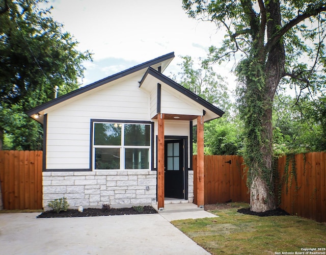 view of front facade featuring stone siding and fence