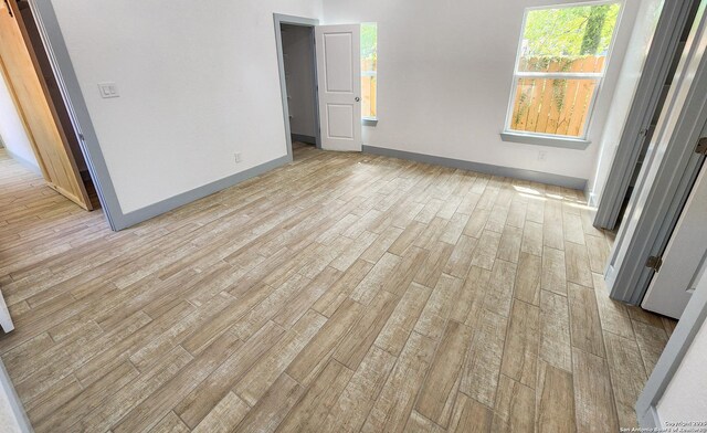empty room with light wood-type flooring and baseboards