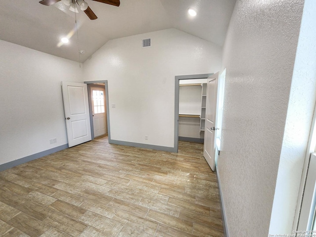 unfurnished bedroom featuring light wood-style floors, lofted ceiling, a spacious closet, baseboards, and ceiling fan