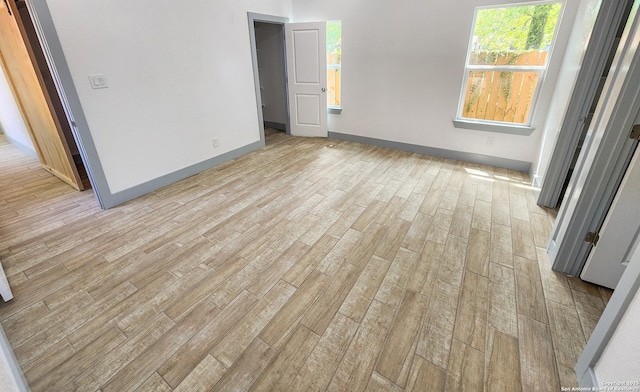 empty room with light wood-type flooring and baseboards