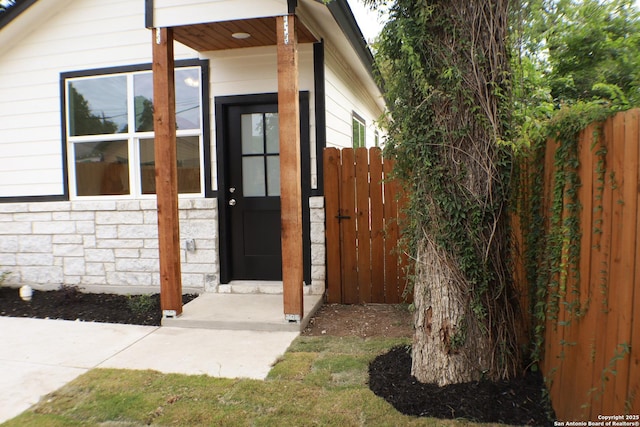 entrance to property with stone siding and fence