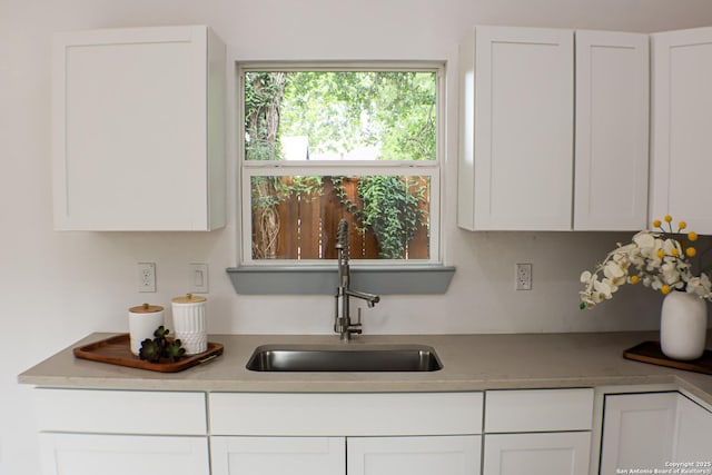 kitchen with a sink, white cabinets, and light countertops