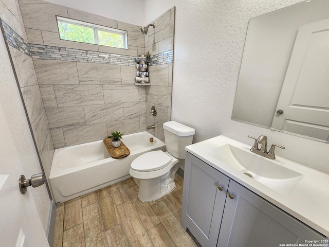 bathroom with wood finished floors, toilet, bathtub / shower combination, vanity, and a textured wall