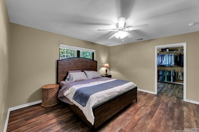 bedroom featuring baseboards, wood finished floors, a spacious closet, a closet, and a ceiling fan