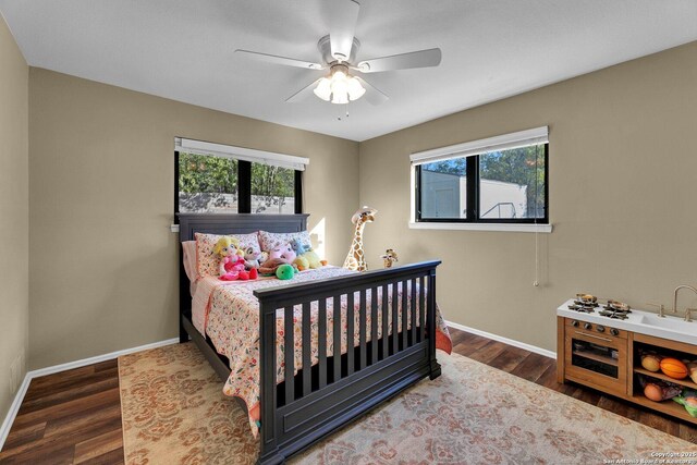 bedroom featuring multiple windows, wood finished floors, baseboards, and a ceiling fan