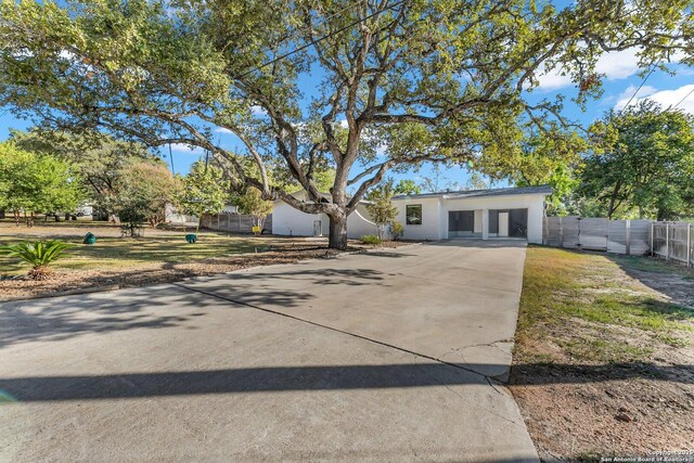 view of front facade featuring driveway, fence, and stucco siding