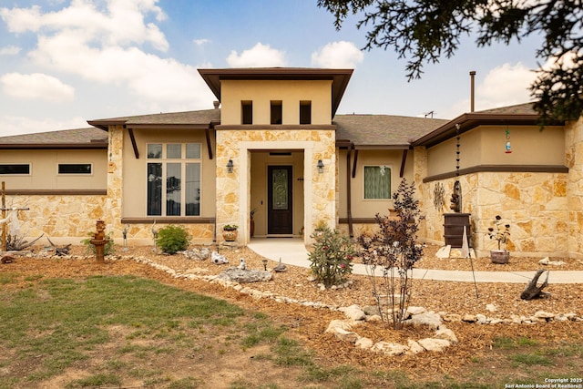 prairie-style home featuring stone siding, stucco siding, and roof with shingles