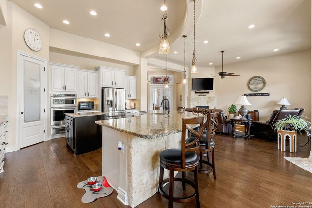 kitchen with stainless steel appliances, a spacious island, a sink, open floor plan, and recessed lighting