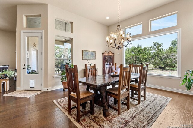 dining room with dark wood finished floors, a chandelier, baseboards, recessed lighting, and a high ceiling