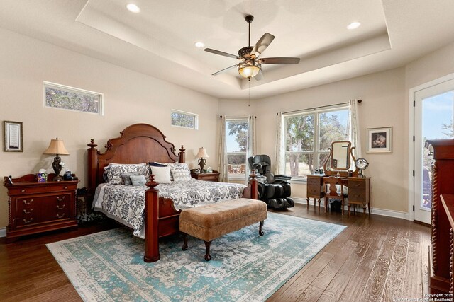 bedroom with a tray ceiling, wood finished floors, baseboards, and recessed lighting
