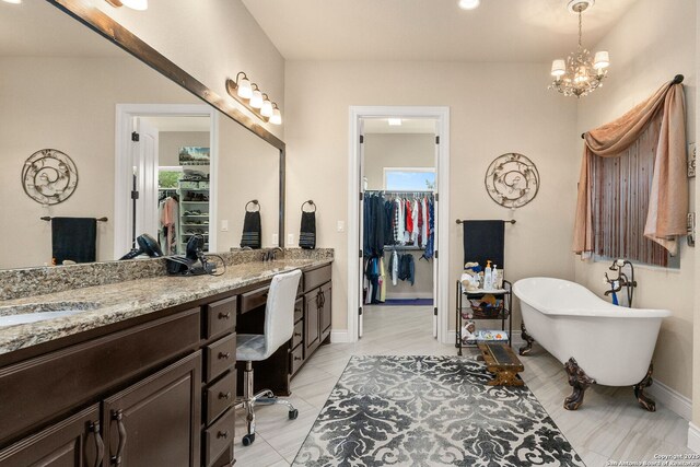 full bathroom featuring double vanity, a walk in closet, a soaking tub, a chandelier, and baseboards
