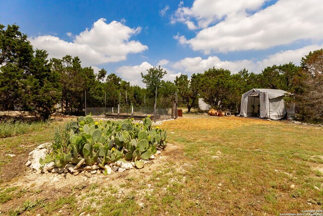 view of green lawn with a storage unit, a garden, and an outbuilding