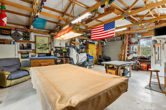 recreation room with a workshop area, concrete floors, and vaulted ceiling