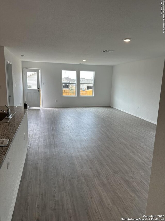 10742 Hernando Ct, Converse, TX 78109 - unfurnished living room featuring dark wood-style flooring, a sink, and baseboards