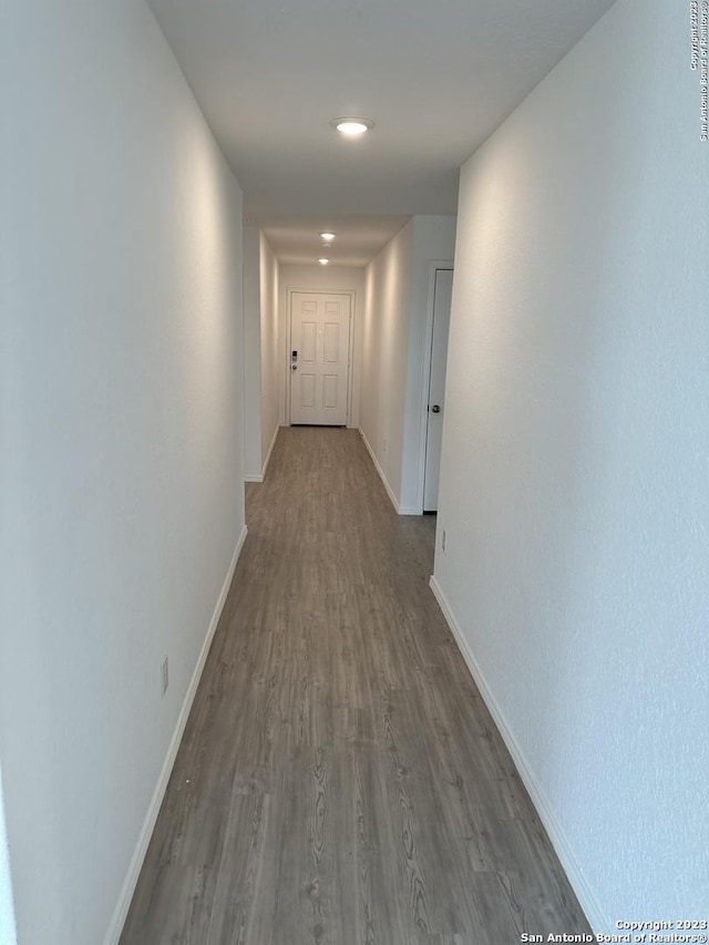 corridor featuring dark wood-style floors, baseboards, and recessed lighting