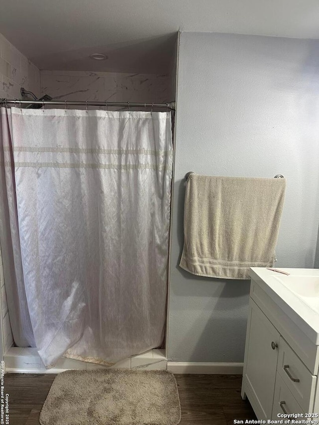 bathroom with a shower with shower curtain, vanity, wood finished floors, and baseboards