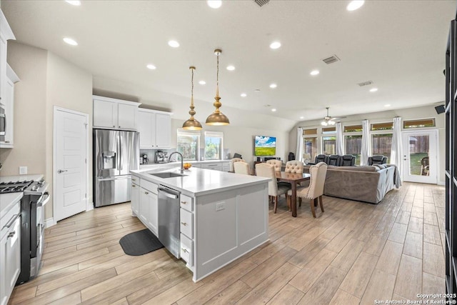 kitchen featuring appliances with stainless steel finishes, a kitchen island with sink, ceiling fan, a sink, and open floor plan