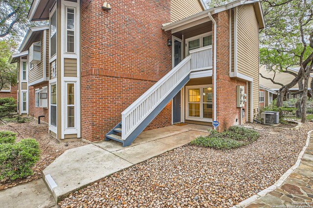 view of exterior entry with central AC unit and brick siding
