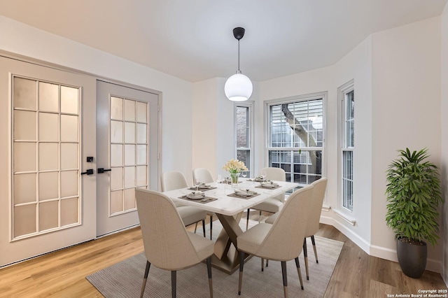 dining room with light wood-style floors, french doors, and baseboards