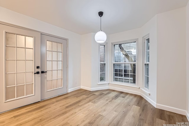 unfurnished dining area featuring light wood-type flooring and baseboards