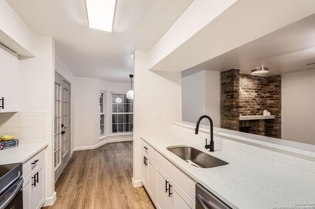 kitchen featuring a sink, light wood-style floors, white cabinetry, and decorative backsplash