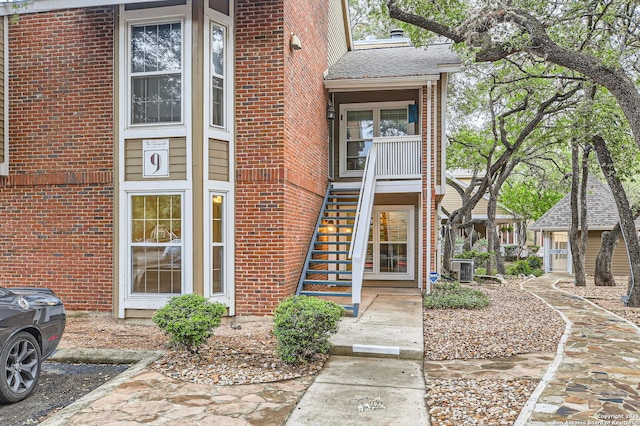 view of exterior entry with brick siding and central AC unit