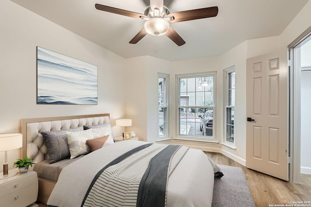 bedroom with light wood-style flooring, a ceiling fan, and baseboards