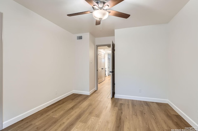 spare room featuring baseboards, light wood finished floors, and ceiling fan