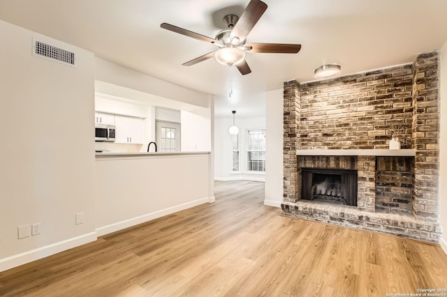unfurnished living room featuring baseboards, wood finished floors, a ceiling fan, and a fireplace