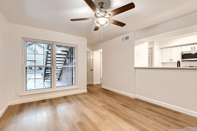 spare room featuring baseboards, ceiling fan, and light wood-type flooring